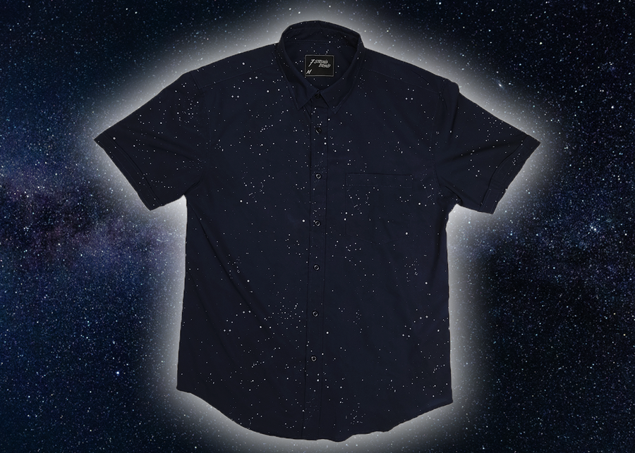 Full view of the short-sleeve Stargazer button down shirt. A deep navy blue shirt with constellation star patterns throughout. The shirt is displayed against a night sky full of stars.