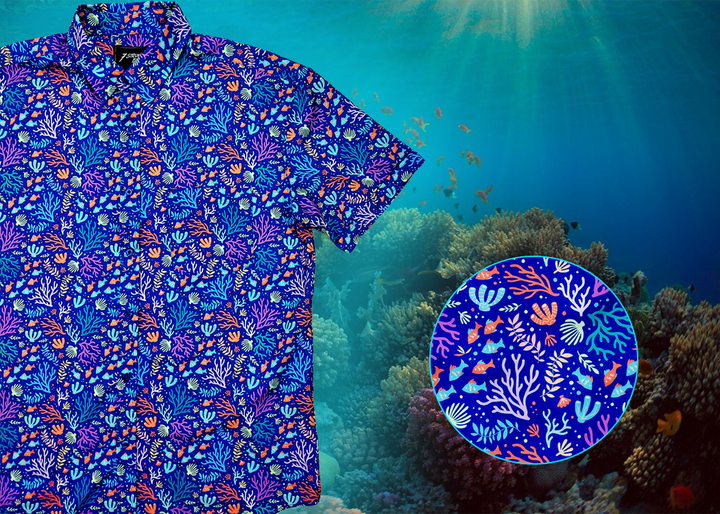 A 3/4 close-up shot of the 7-Strong "Coral of the Story" adult button down shirt. Color of the shirt is blue with vibrant purple, teal, orange sea life imagery - particularly fish and coral reef. The shirt is shown against an underwater background showcasing coral. In the bottom right corner is a close up circle highlight the shirt design details. 