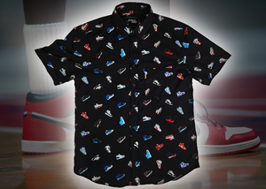 Full view of the adult short sleeve version of "Got 'Em!" The button down features various athletic fashion sneakers in an 8-bit format arranged all over a black shirt. The shirt is featured against a background of a basketball player on the court, noticeable sneakers being worn
