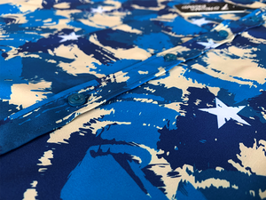 Middle button area close up of the 7-Strong "Service Stars" Adult button-up, featuring blue and creme colored camouflage with white weathered stars throughout.