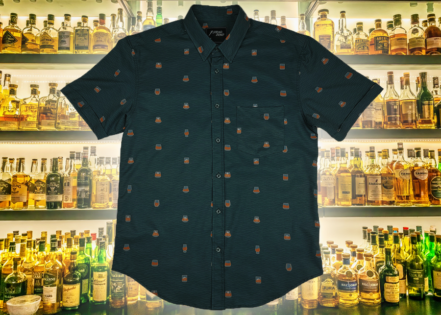 Full display view of the 7-Strong "Straight Sippin'" Short Sleeve button down. The shirt is a deep green with black ripples as its background, while the foreground has various drinking glasses with various levels of whiskey, some with ice, others without. The shirt is shown against a background of various whiskies and bourbons on a shelf.