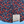 Load image into Gallery viewer, Bottom half sweep tag view of the 7-Strong &quot;Aye Poppy&quot; button down, featuring an array of red poppys with white sprigs on a deep navy blue shirt. The shirt is displayed against a partly cloudy sky.
