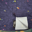 Load image into Gallery viewer, Sweep tag sectional shot of the 7-Strong &quot;Mine Train&quot; adult button up. Shirt is a deep purple with a rock quarry depicting ghosted design showcasing various colors of gemstones and mine train carts throughout. The shirt itself is displayed against a background of a mine shaft and various gems found in buckets. 
