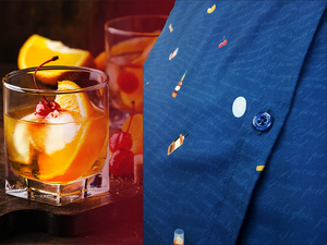 Side view layout of "Call Me Old Fashioned" adult short sleeve button-down. Features elements of an Old Fashioned cocktail (bottle of bourbon, glasses, oranges, stirrers, and ice) against a blue background which faintly spells out an Old Fashioned recipe. Shirt is on a background featuring a finished Old Fashioned and has a detail circle in the bottom corner showing design detail. 
