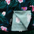 Load image into Gallery viewer, Bottom sweep tag view of the Youth 7-Strong &quot;Tropic Like It&#39;s Hot&quot; button down shirt - a black shirt with distinctive green palm trees and pink, white, and purple flowers peering out from behind the palms. Shirt is shown on a tropical rainforest background.
