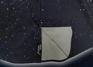 Bottom sweep tag portion view of the short-sleeve Stargazer button down shirt. A deep navy blue shirt with constellation star patterns throughout. The shirt is displayed against a night sky full of stars.