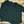 Load image into Gallery viewer, Full display view of the 7-Strong &quot;Straight Sippin&#39;&quot; Short Sleeve and long-sleeve button downs, overlapping each other. The shirt is a deep green with black ripples as its background, while the foreground has various drinking glasses with various levels of whiskey, some with ice, others without. The shirt is shown against a background of various whiskies and bourbons on a shelf.
