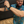 Load image into Gallery viewer, Medium view of male model swinging a steel chair at camera, wearing the 7-Strong &quot;TLC OMG&quot; shirt, a homage to wrestling objects featured all over the shirt including tables, ladders, chairs, ring bells, sledgehammers, brass knuckles, championships, guitars, stop signs, microphones amongst other items. The items are on a blue shirt with a faded steel cage background. The shirt is featured on a background of a wrestling ring with a standing ladder. 
