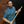 Load image into Gallery viewer, Full view male model holding a kendo stick against a brick wall,wearing  the 7-Strong &quot;TLC OMG&quot; shirt, a homage to wrestling objects featured all over the shirt including tables, ladders, chairs, ring bells, sledgehammers, brass knuckles, championships, guitars, stop signs, microphones amongst other items. The items are on a blue shirt with a faded steel cage background. The shirt is featured on a background of a wrestling ring with a standing ladder. 

