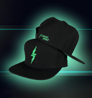 Black snapback hat on a futuristic background, hat features the mint version of the 7-Strong bolt logo. One hat is stacked on top of the other, with the top one illustrating the scripted logo branded by the snaps. 