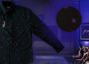 3/4 full view of the 7-Strong "Flux Capacity" long sleeve button down, showcasing bursts and lines of purple light peering through a black grid of cubes. The background is of a fashion show runway in purple hue. Off centered on the right is a detail circle showcasing the shirt's design.