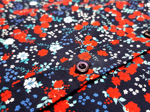 Close up of the middle button region of the "Aye Poppy" long sleeve button up, showcasing the red poppies and white sprigs against the deep navy blue background. 