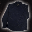 Load image into Gallery viewer, Full view of the long-sleeve Stargazer button down shirt. A deep navy blue shirt with constellation star patterns throughout. The shirt is displayed against a night sky full of stars. 
