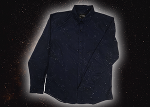 Full view of the long-sleeve Stargazer button down shirt. A deep navy blue shirt with constellation star patterns throughout. The shirt is displayed against a night sky full of stars. 