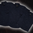 Load image into Gallery viewer, Full view of the long-sleeve, and short-sleeve adult and youth Stargazer button down shirts overlapping one another. A deep navy blue shirt with constellation star patterns throughout. The shirt is displayed against a night sky full of stars. 
