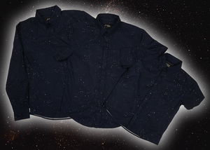 Full view of the long-sleeve, and short-sleeve adult and youth Stargazer button down shirts overlapping one another. A deep navy blue shirt with constellation star patterns throughout. The shirt is displayed against a night sky full of stars. 