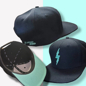 Black snapback hat on a mint and white background, hat features the mint version of the 7-Strong bolt logo. Shows the back full brand name, another angle of the hat is shown with the under brim mint coloring and 7-Strong script logo lining, and an angle of the 7-Bolt logo on the front of hat 