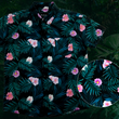 Load image into Gallery viewer, Full view of the Youth 7-Strong &quot;Tropic Like It&#39;s Hot&quot; button down shirt - a black shirt with distinctive green palm trees and pink, white, and purple flowers peering out from behind the palms. Shirt is shown on a tropical rainforest background. Bottom right of the photo shows a circle detailing the flowers and palms on the shirt in closeup. 
