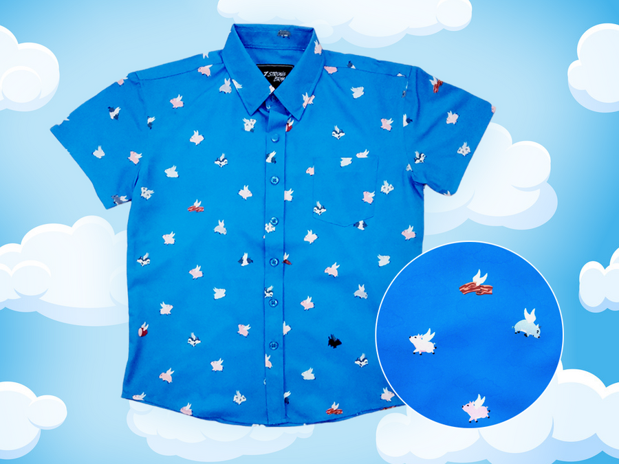 Full shot of the 7-Strong "When Pigs Fly" shirt, showcasing various pigs and meats flying against a blue, muted cloud background. Shirt is displayed against a background of cartoon clouds. Bottom right features a circle which details the flying pigs featured on the shirt. 