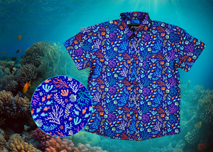 Full view shot of the 7-Strong "Coral of the Story" youth button down shirt. Color of the shirt is blue with vibrant purple, teal, orange sea life imagery - particularly fish and coral reef. The shirt is shown against an underwater background showcasing coral. In the left corner, there is a close up circle showcasing the details of the shirt. 