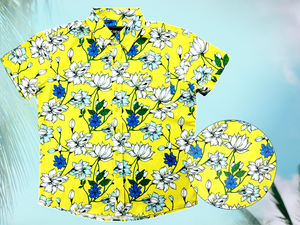 Full view of the 7-Strong "Late Bloomer" youth button down - a yellow background shirt with white and blue flowers patterned all over it. Shirt is against a blue tropical sky with palm trees in the distance. Bottom right of photo has a detail circle which showcases the flowers on the shirt. 