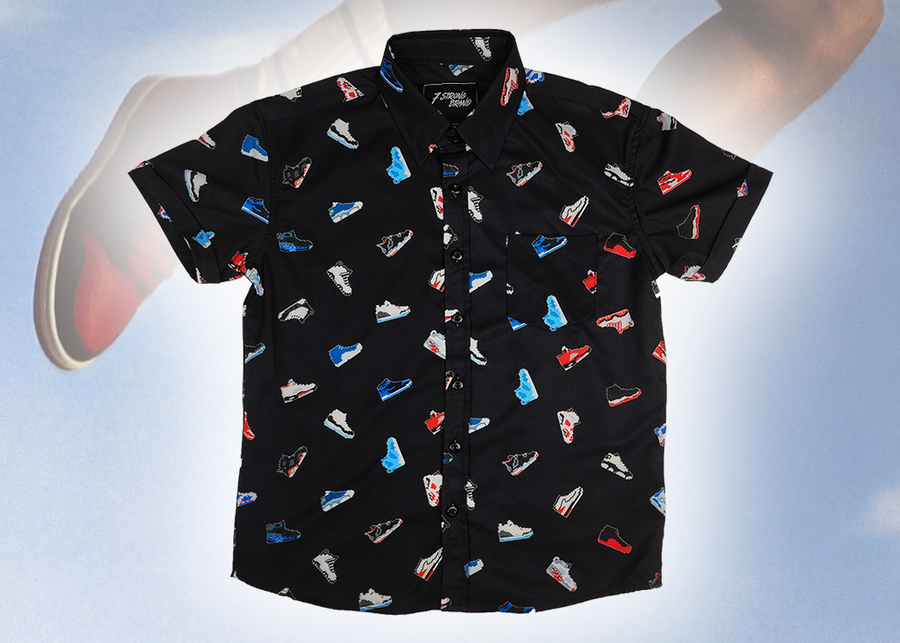 Full centered view of the youth short sleeve version of "Got 'Em!" The button down features various athletic fashion sneakers in an 80bit format arranged all over a black shirt. The shirt is featured against a background of a basketball player jumping in air, noticeable sneakers being worn. 