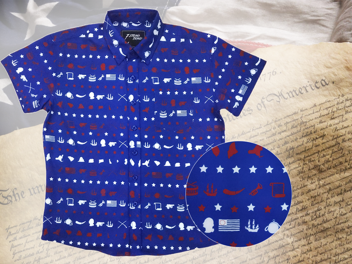 A full representation of 7-Strong's youth 1776 button down shirt against a Declaration of Independence background. Shirt is royal blue with stripes of various Americana icons, including the original 13 colonies and revolutionary war items. On the right of the picture, there is a close-up circle giving detail to the various icons on the shirt.