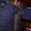 Load image into Gallery viewer, Full view shot of the 7-Strong &quot;Mine Train&quot; adult button up. Shirt is a deep purple with a rock quarry depicting ghosted design showcasing various colors of gemstones and mine train carts throughout. The shirt itself is displayed against a background of a mine shaft and various gems found in buckets. On the right side there is a detail circle showcasing the design up close. 
