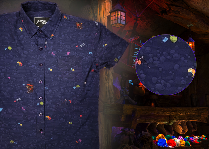 Full view shot of the 7-Strong "Mine Train" adult button up. Shirt is a deep purple with a rock quarry depicting ghosted design showcasing various colors of gemstones and mine train carts throughout. The shirt itself is displayed against a background of a mine shaft and various gems found in buckets. On the right side there is a detail circle showcasing the design up close. 