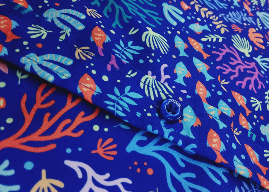 Mid torso view of the 7-Strong "Coral of the Story" youth button down shirt. Color of the shirt is blue with vibrant purple, teal, orange sea life imagery - particularly fish and coral reef. 