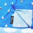 Load image into Gallery viewer, Close up shot of sweep tag region of the 7-Strong &quot;When Pigs Fly&quot; shirt, showcasing various pigs and meats flying against a blue, muted cloud background. Shirt is displayed against a background of cartoon clouds.
