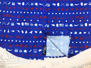 A close-up representation of 7-Strong's youth 1776 button down shirt, focused on the sweep tag region, against a Declaration of Independence background. Shirt is royal blue with stripes of various Americana icons, including the original 13 colonies and revolutionary war items.