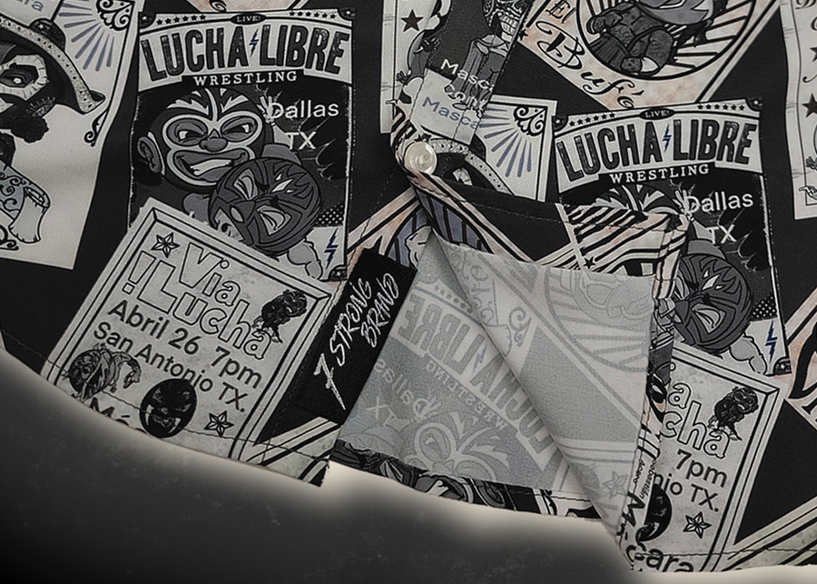 Bottom sweep tag view of the youth 7-Strong "Cinco de Mayhem" button down shirt. Shirt features black and white posters featuring various created luchadors advertised for matches, all overlapping each other over a black shirt. Shirt is displayed on a black gradient background with some of the characters ghosted in the back.