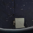 Load image into Gallery viewer, Bottom sweep tag portion view of the short-sleeve youth Stargazer button down shirt. A deep navy blue shirt with constellation star patterns throughout. The shirt is displayed against a night sky full of stars.

