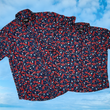 Load image into Gallery viewer, Full, overlapping view of the adult and youth 7-Strong &quot;Aye Poppy&quot; button down, featuring an array of red poppys with white sprigs on a deep navy blue shirt. The shirt is displayed against a partly cloudy sky. 
