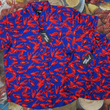 Load image into Gallery viewer, Full view of the both the youth and adult 7-Strong Dat Boil shirts side-by-side in deep navy blue with red crawfish patterned throughout overlapping one another. The shirt itself sits on a background image of items from a Crawfish Boil such as crawfish, seasoning, corn, and potatoes. 

